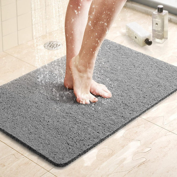 Person standing on a quick-drying grey shower mat under running water