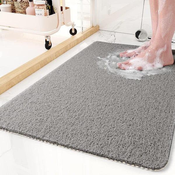 Grey non-slip shower mat on tiled bathroom floor with soapy feet
