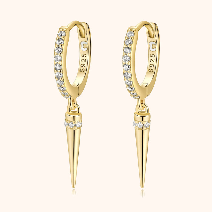 Close-up view of gold zirconia drop earrings on a neutral background