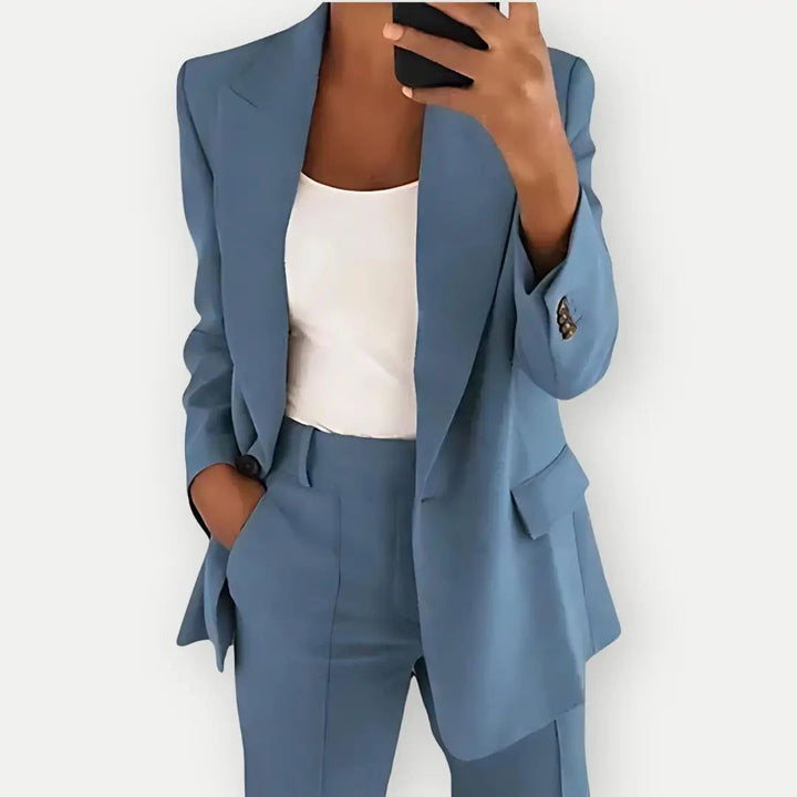 Woman wearing a blue tailored blazer and pants set taking a mirror selfie