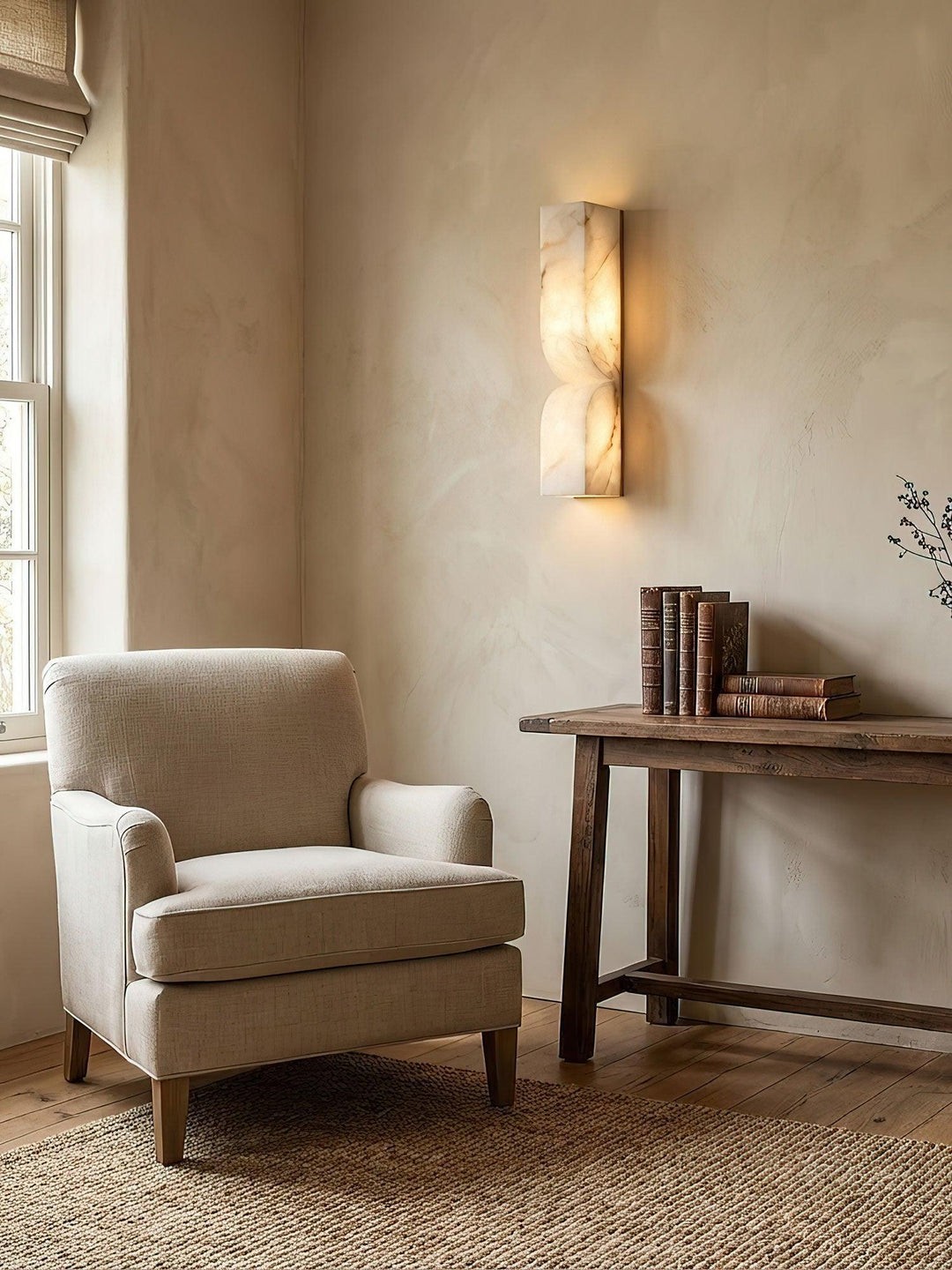 Alabaster wall lamp mounted on a textured beige wall in a cozy living room setting next to an armchair.