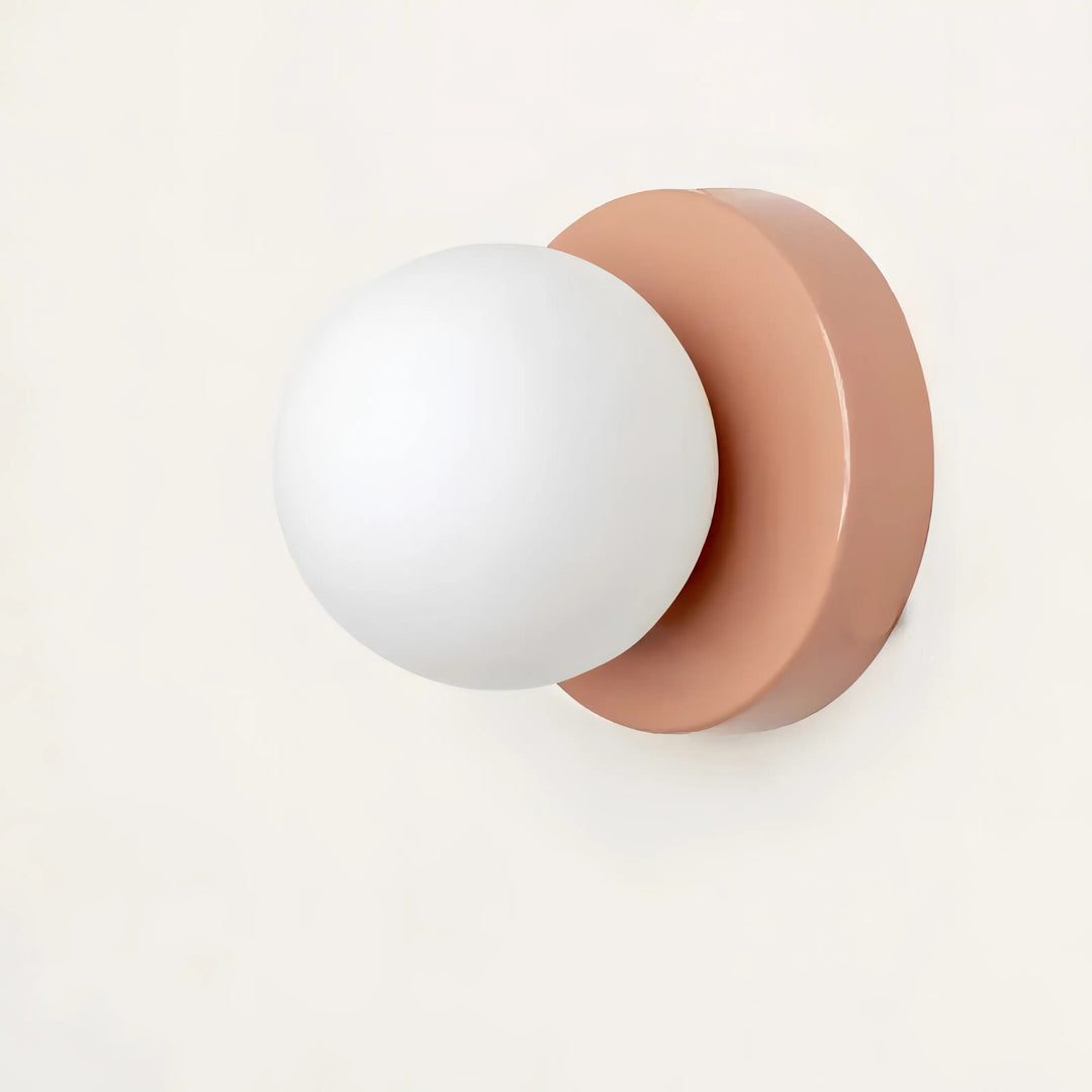 Close-up of a stylish pink and white spherical glass wall light fixture against a white background