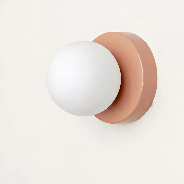 Close-up of a stylish pink and white spherical glass wall light fixture against a white background