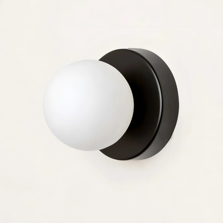 Close-up of the elegant glass wall sconce showing brass mounting details