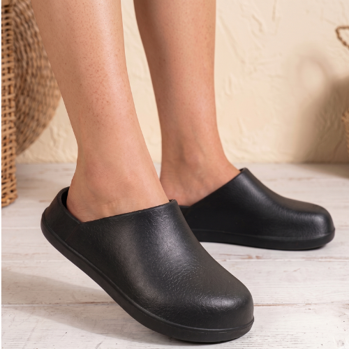 Person wearing black ergonomic slip-on clog mules indoors