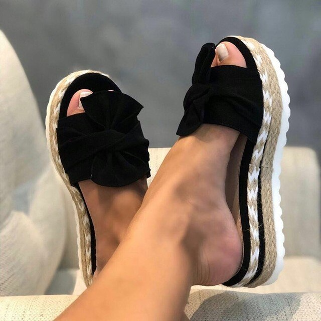 Black woven wedge sandals featuring a stylish front bow