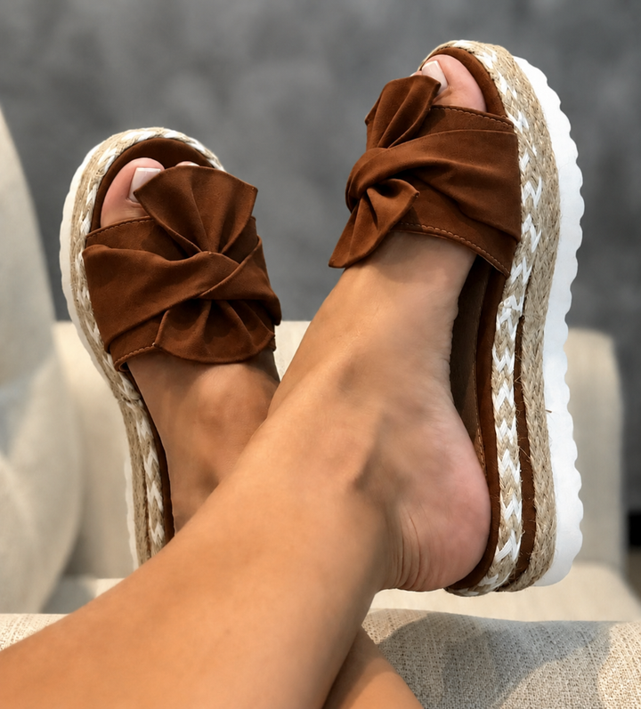 Close-up of the stylish bow detail on the front of chic summer wedge shoes