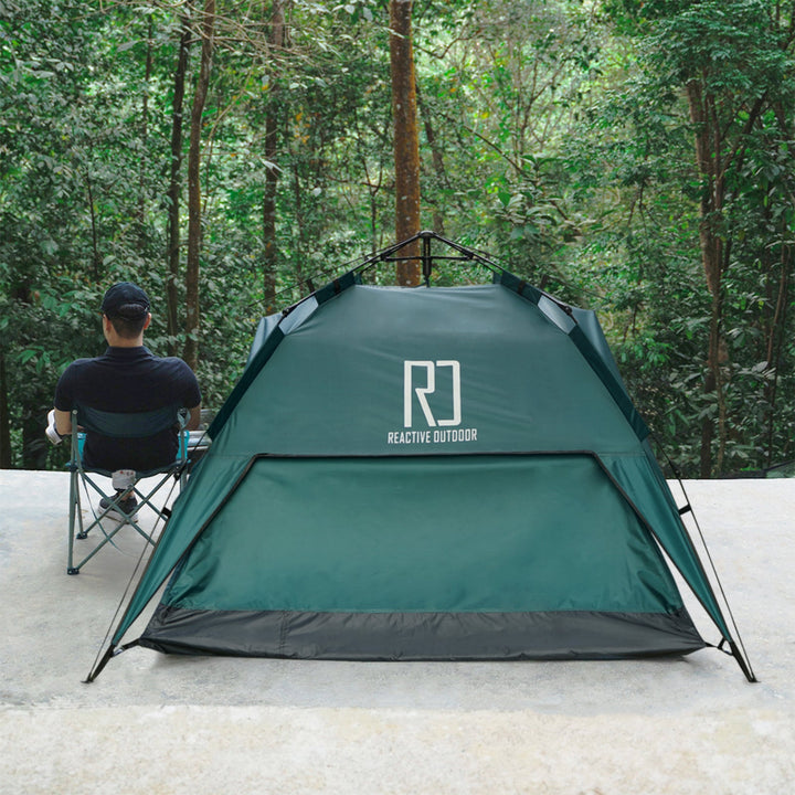 Outdoor camping tent pitched near a forest with a person relaxing