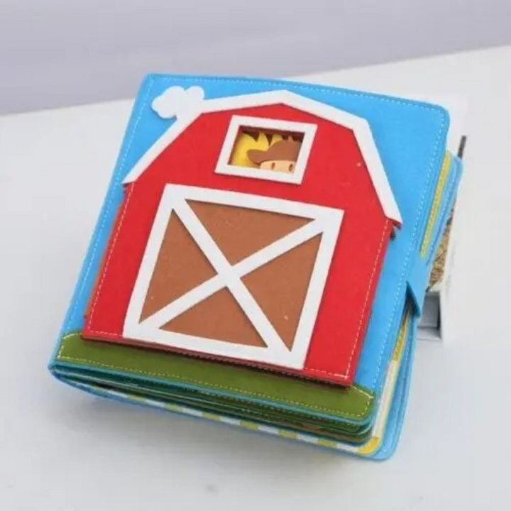 Front view of the blue felt farm adventure quiet book featuring a red barn cover