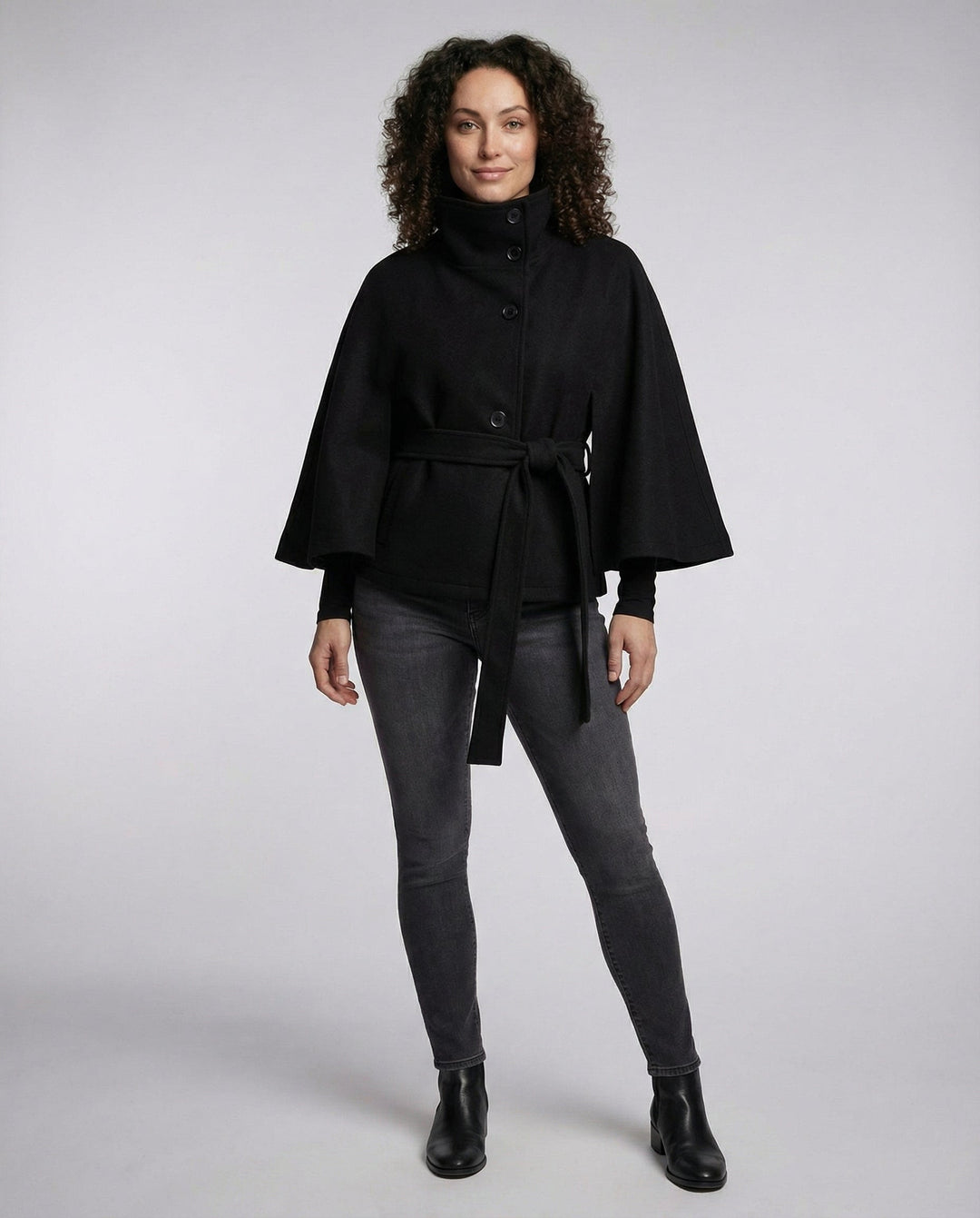 Full-body view of model wearing black wrap jacket and dark jeans