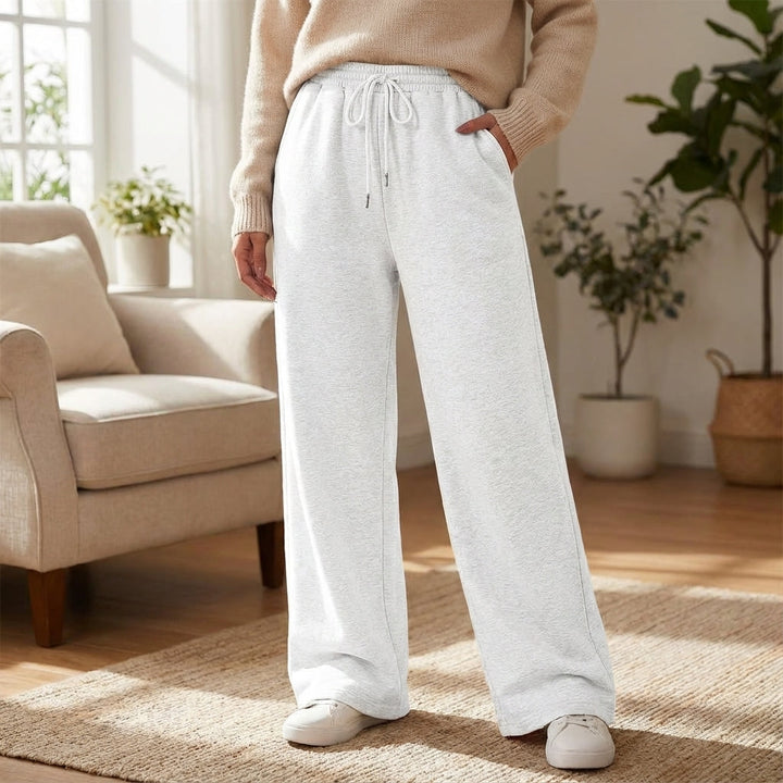 Woman wearing grey wide-leg joggers standing in a cozy living room setting