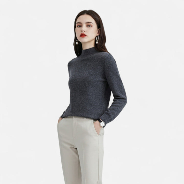 Model wearing women's dark grey mock neck sweater with light trousers