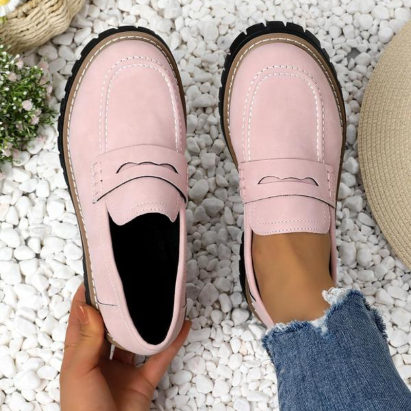 Top down view of pink chunky platform loafers on white pebbles
