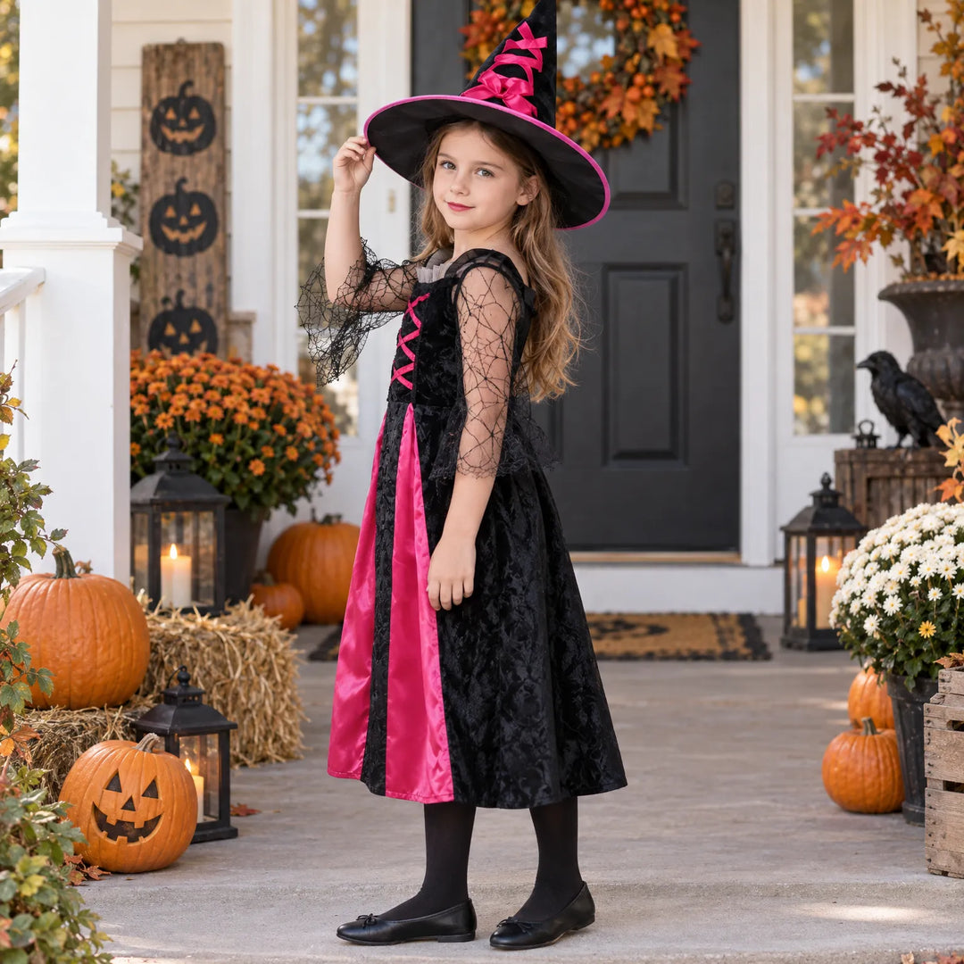 Young girl modeling a black and pink witch costume on a porch decorated for Halloween