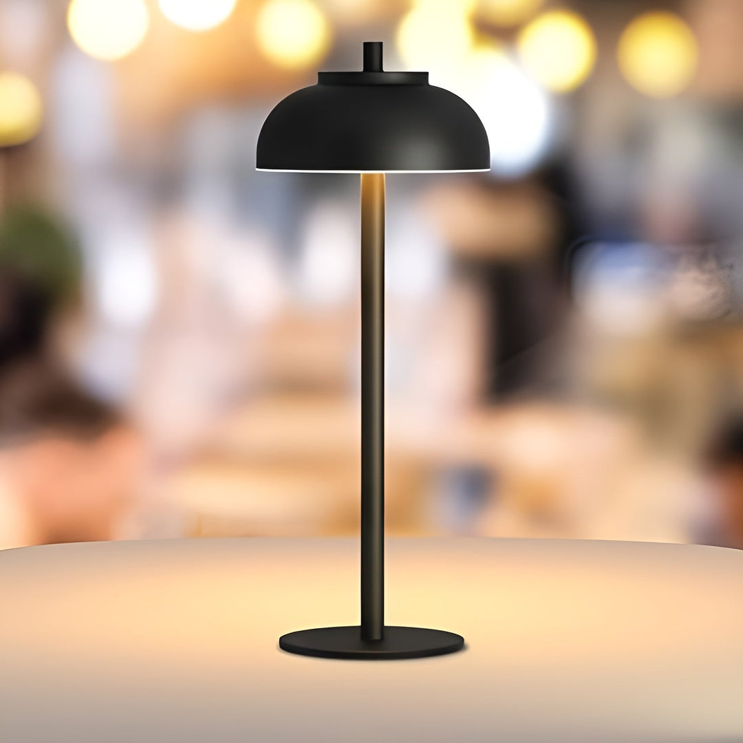 Modern black rechargeable table lamp glowing softly on a tabletop