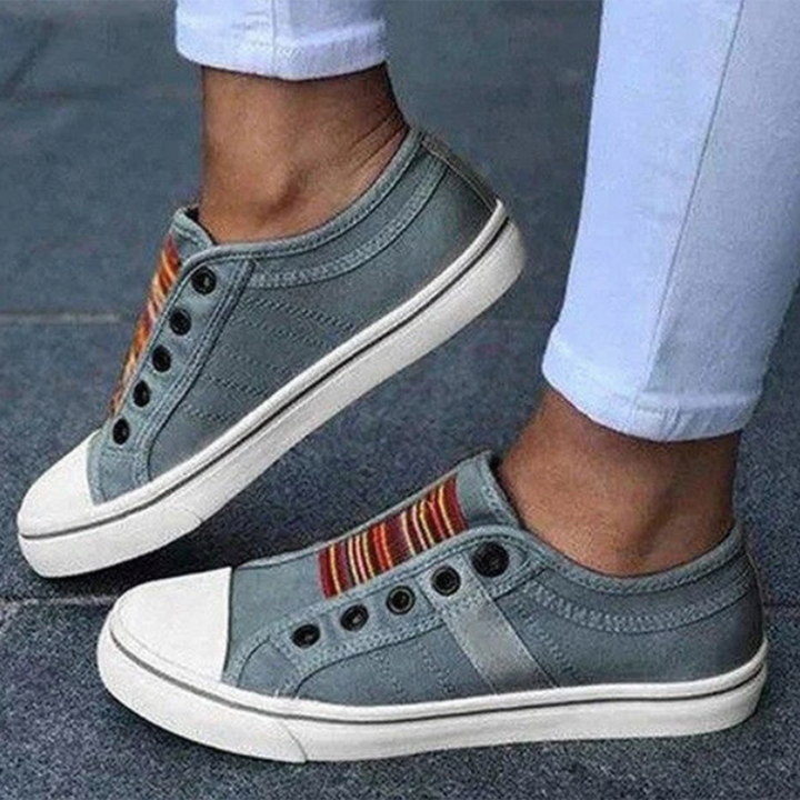 Side angle view of grey slip-on sneakers worn on pavement