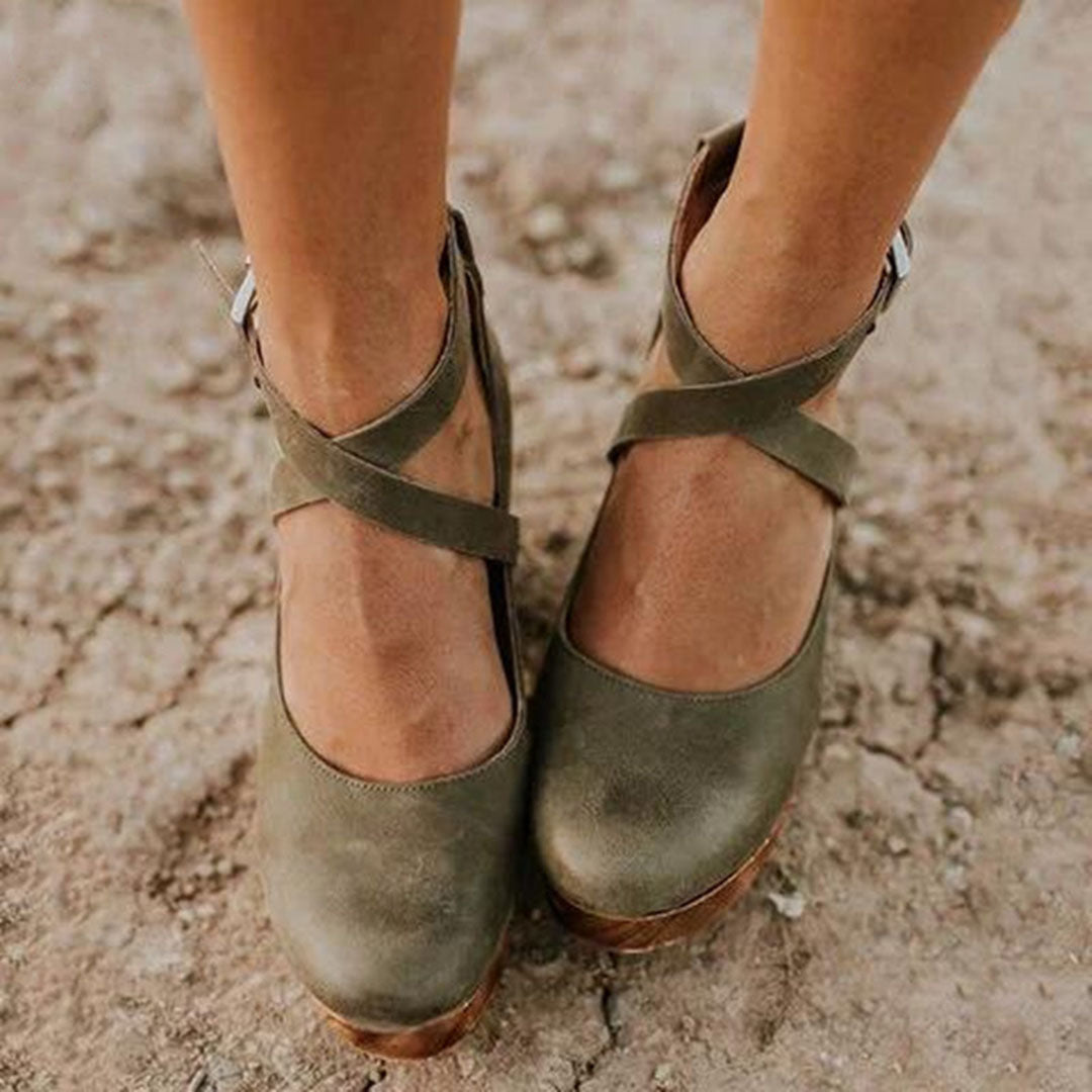 Close-up front view of green wedge heels with supportive buckle strap