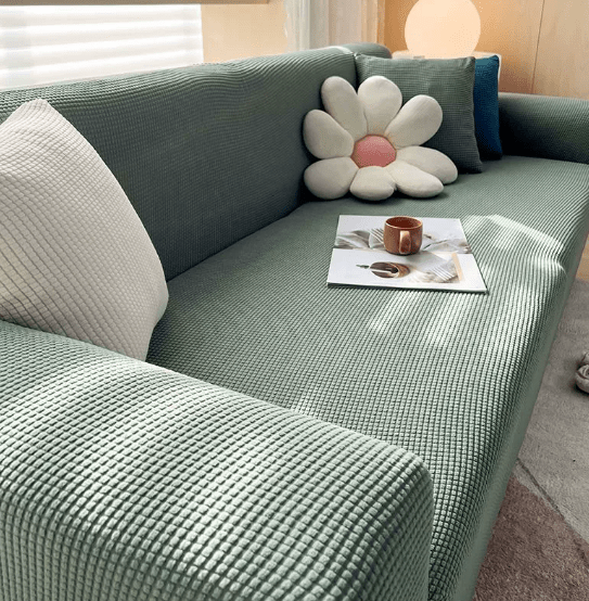 Green sofa cover styled on a couch with decorative cushions