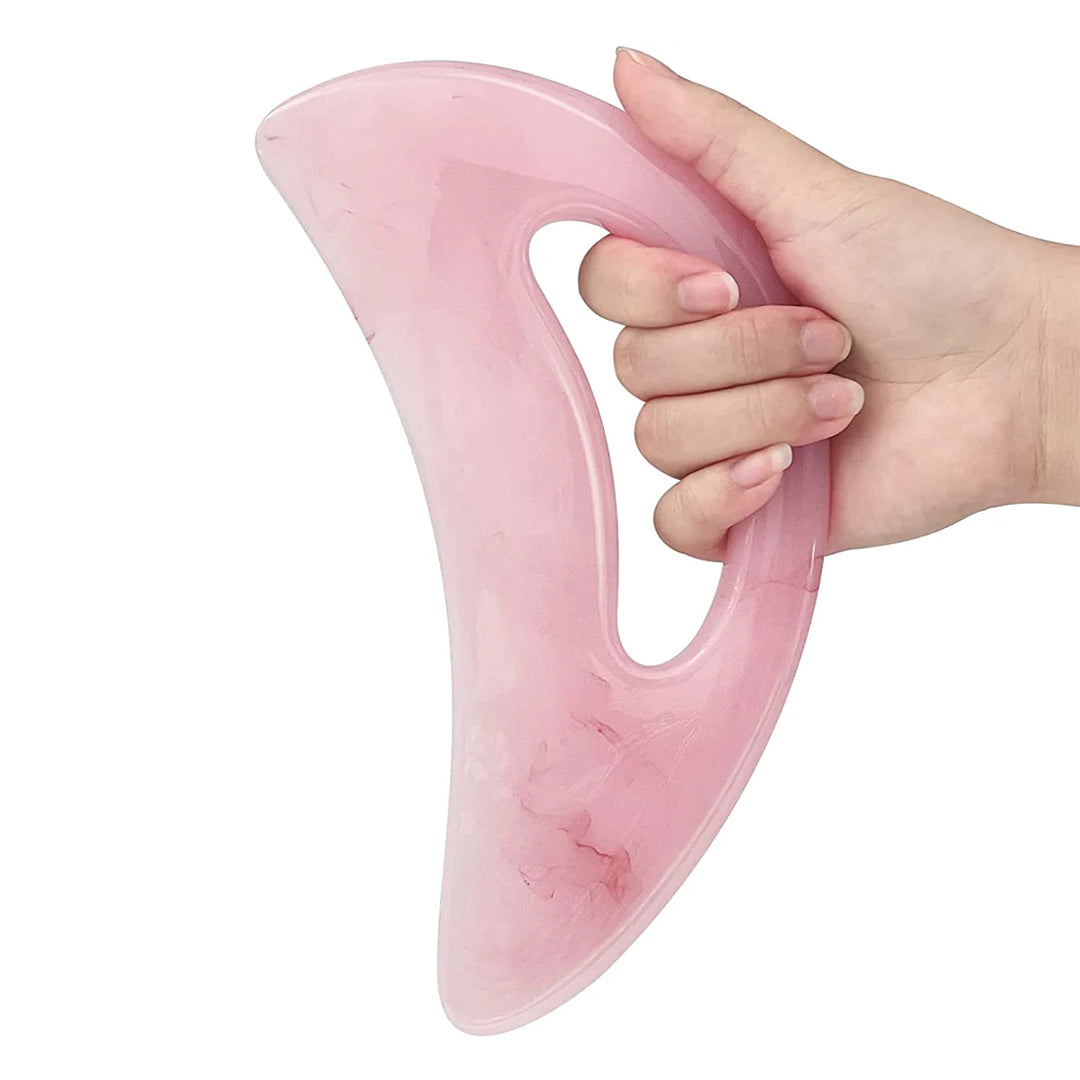 Person holding a pink resin Gua Sha body massager in hand