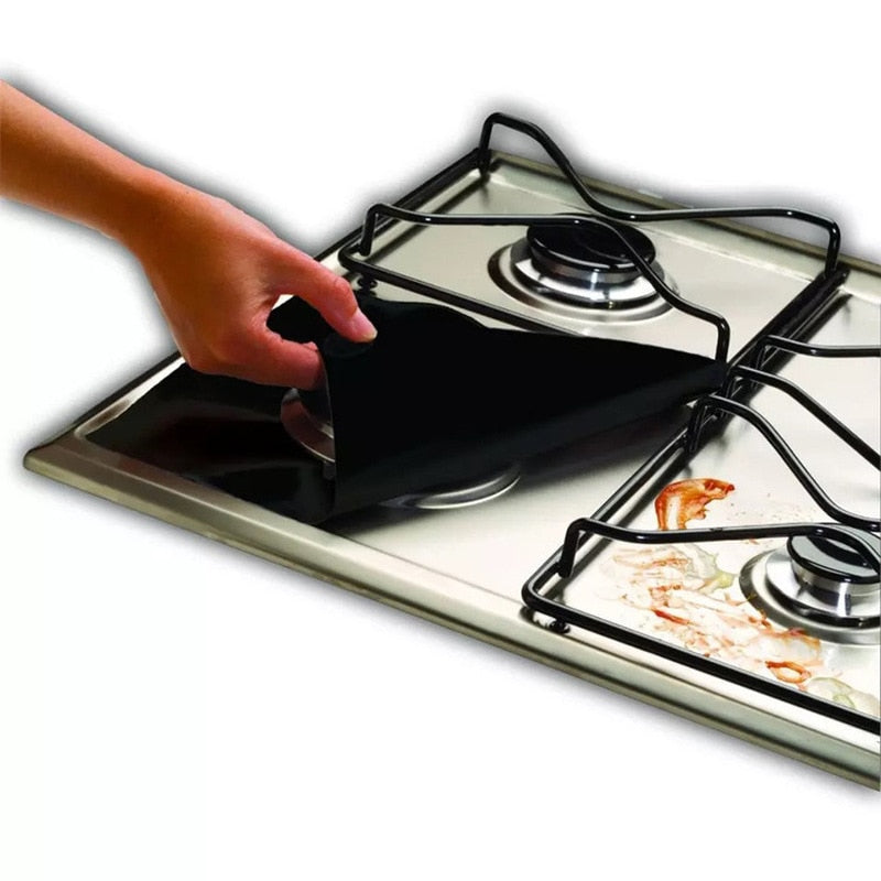 Close-up view of a black gas stove top protector being adjusted over burner components