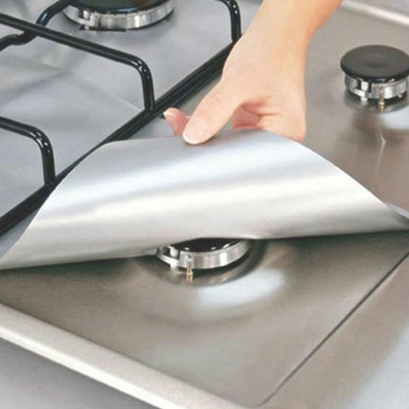 Person placing a silver reusable stove top protector onto a clean gas cooker