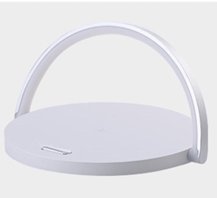 Minimalist LED night lamp and Qi charger glowing warmly in a dark bedroom