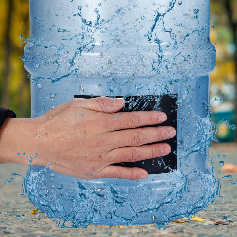 Hand applying black waterproof repair tape over a leak on a large water container