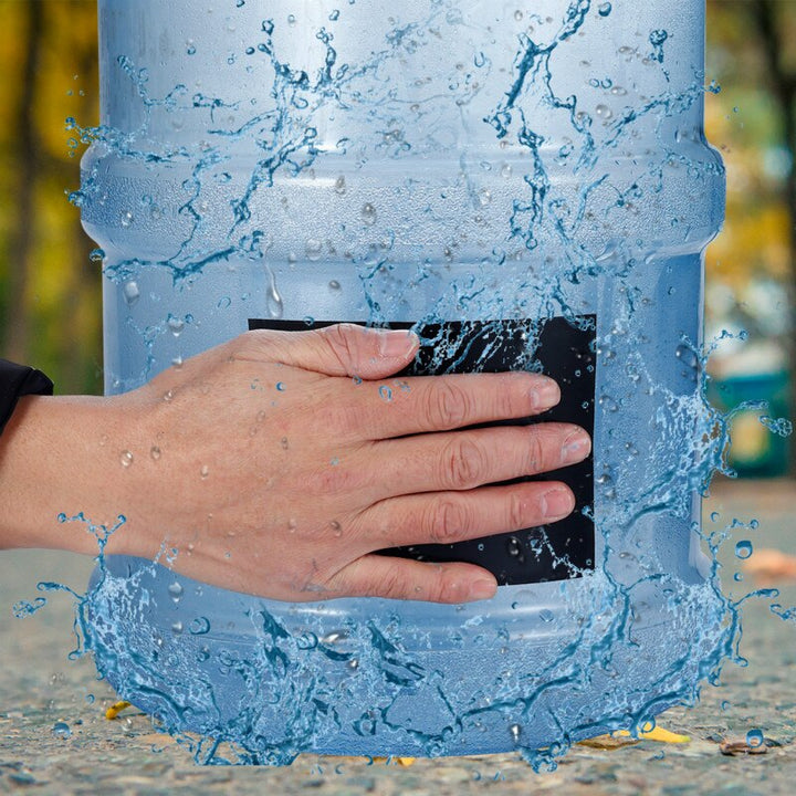 Hand applying black waterproof repair tape over a leak on a large water container