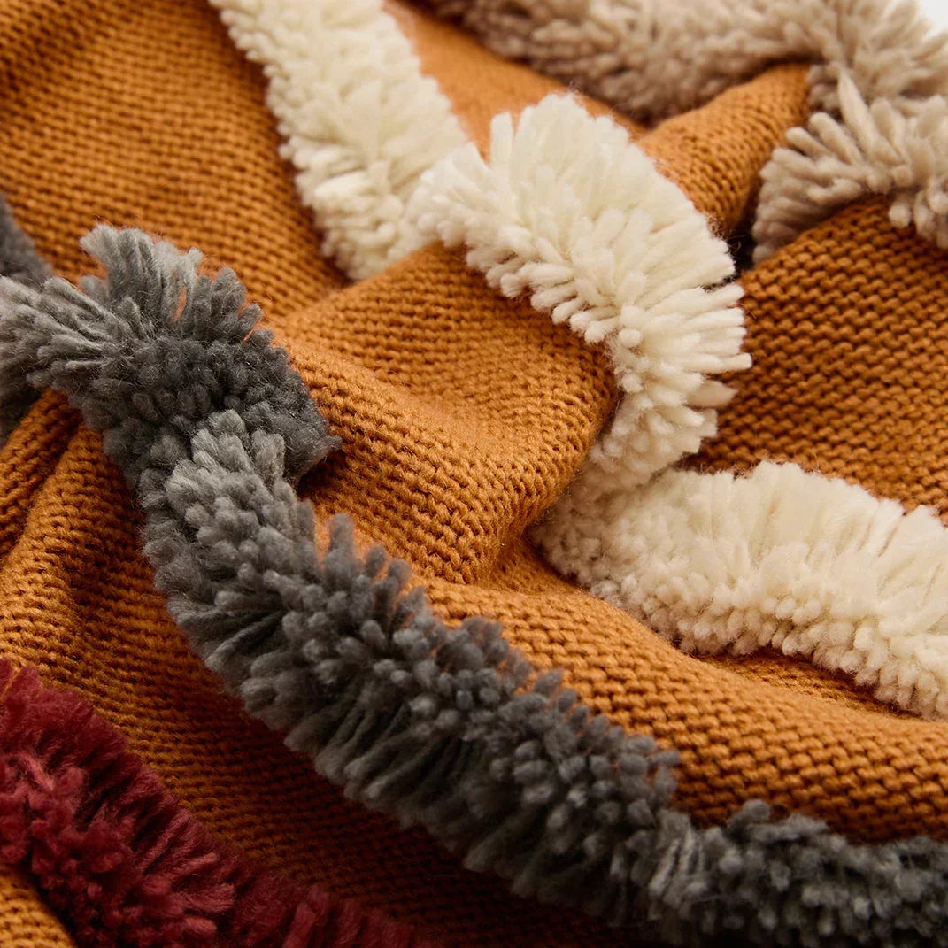 Close-up of textured woven velour fabric with colorful stripes and fringe detail