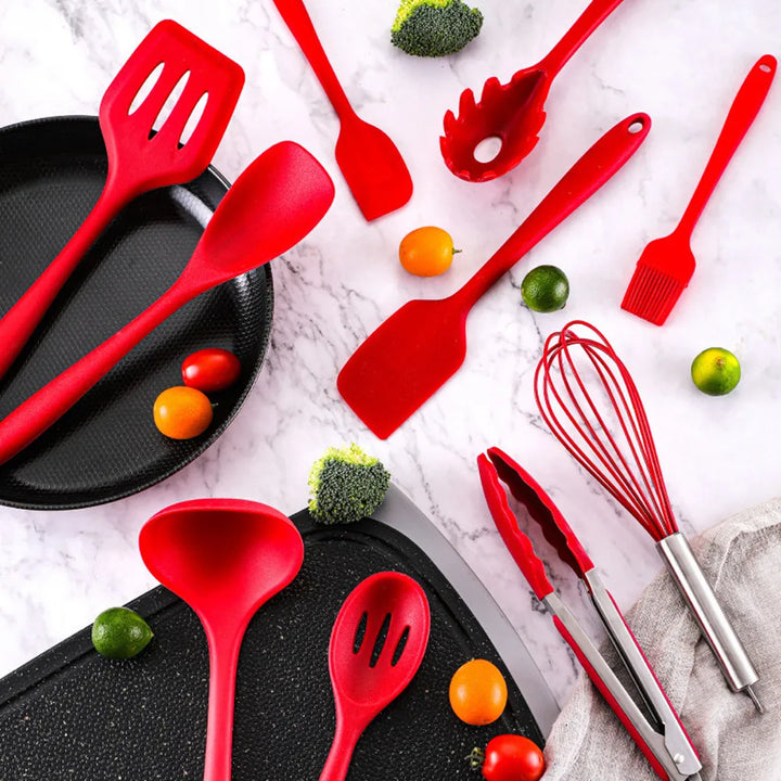 Red silicone kitchen utensils laid out next to fresh cooking ingredients