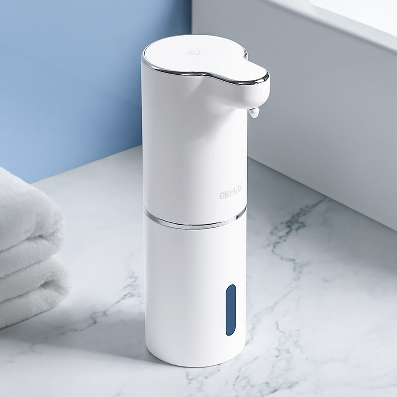 Automatic touchless foaming soap dispenser on a marble countertop next to towels
