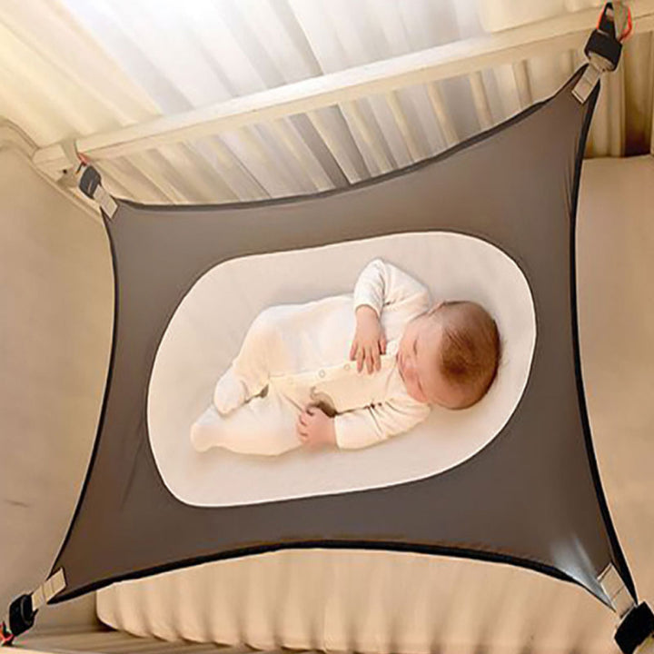 Baby resting comfortably in a grey cot hammock