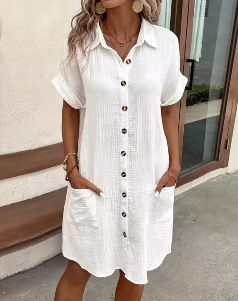 Woman wearing a white casual button-down shirt dress with side pockets