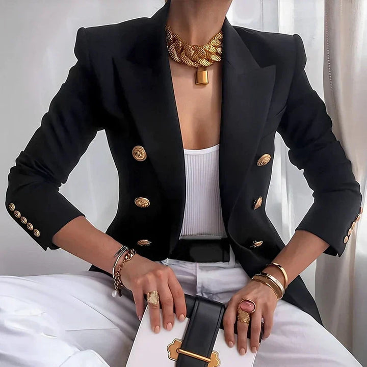 Woman wearing a black tailored double-breasted blazer with gold buttons and a white top