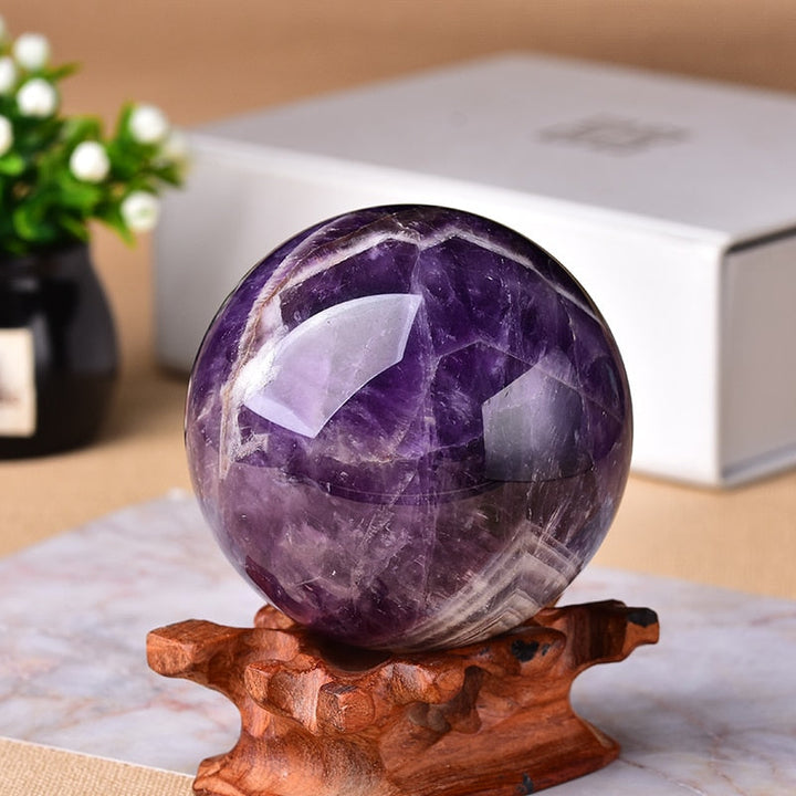 Close-up of a polished amethyst globe gemstone sphere resting on a wooden stand
