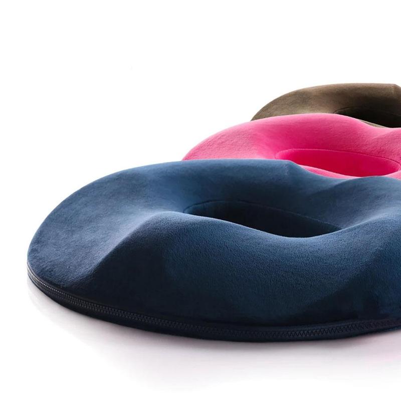 Close-up view of blue, pink, and brown memory foam donut seat cushions stacked together