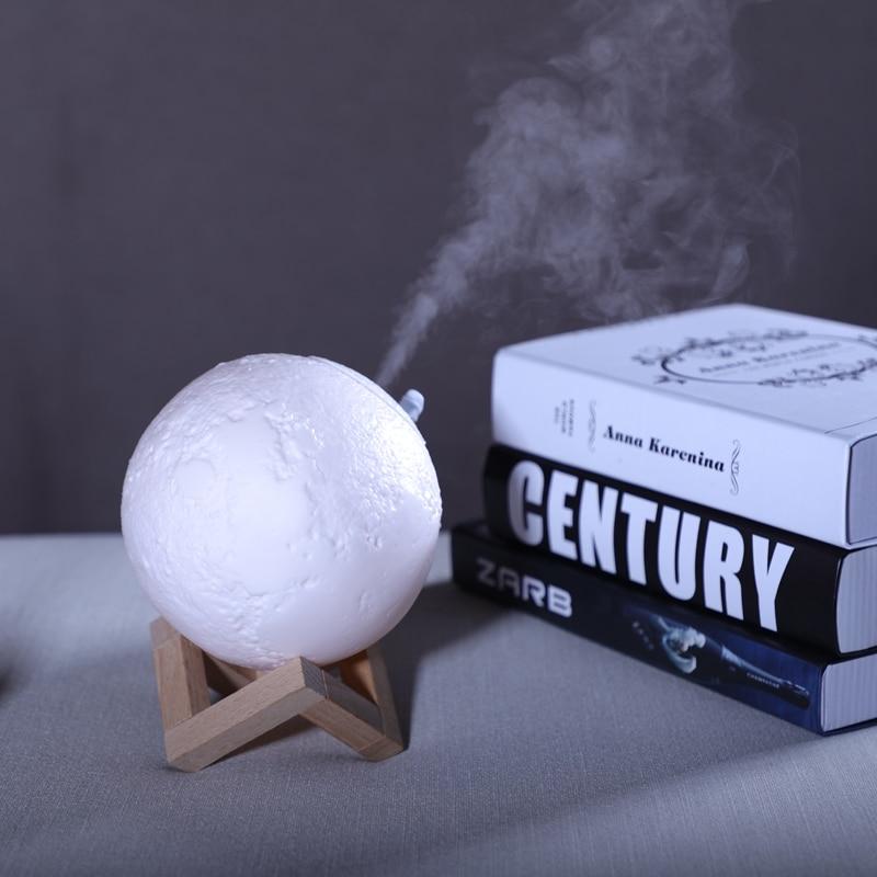 Compact desk air humidifier diffusing mist next to books