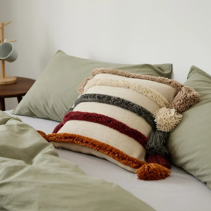 Decorative striped cushion cover styled on a made bed with neutral pillows