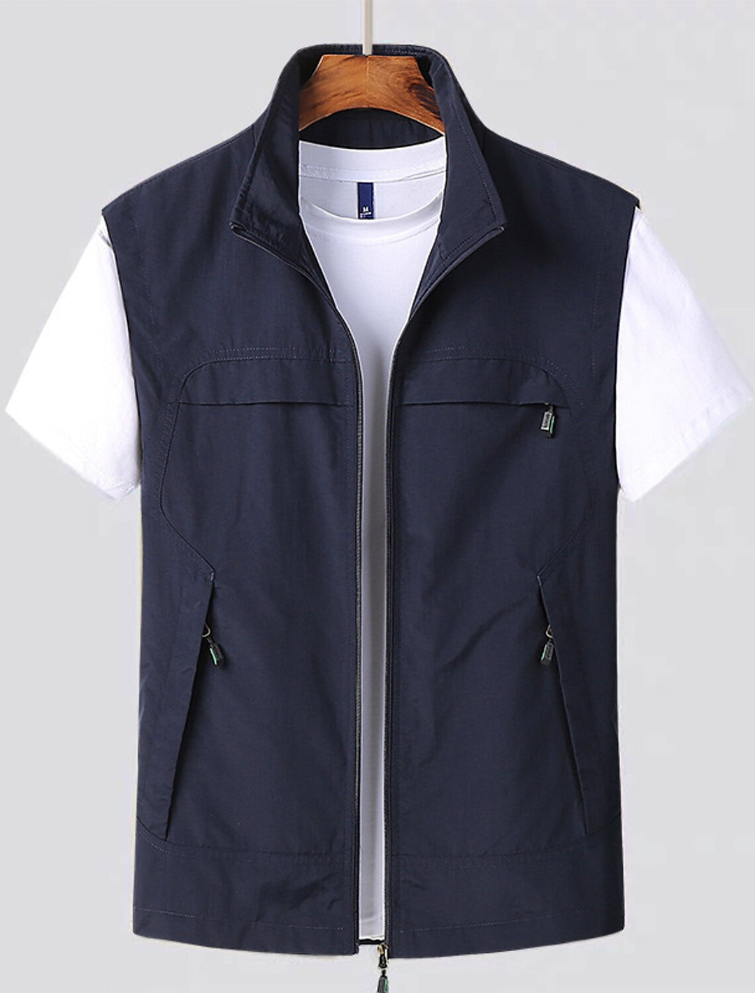 Men's navy blue water-repellent zip utility vest hanging on a display