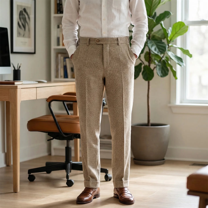 Man wearing beige herringbone slim-cut trousers with a white shirt and loafers in a home office.