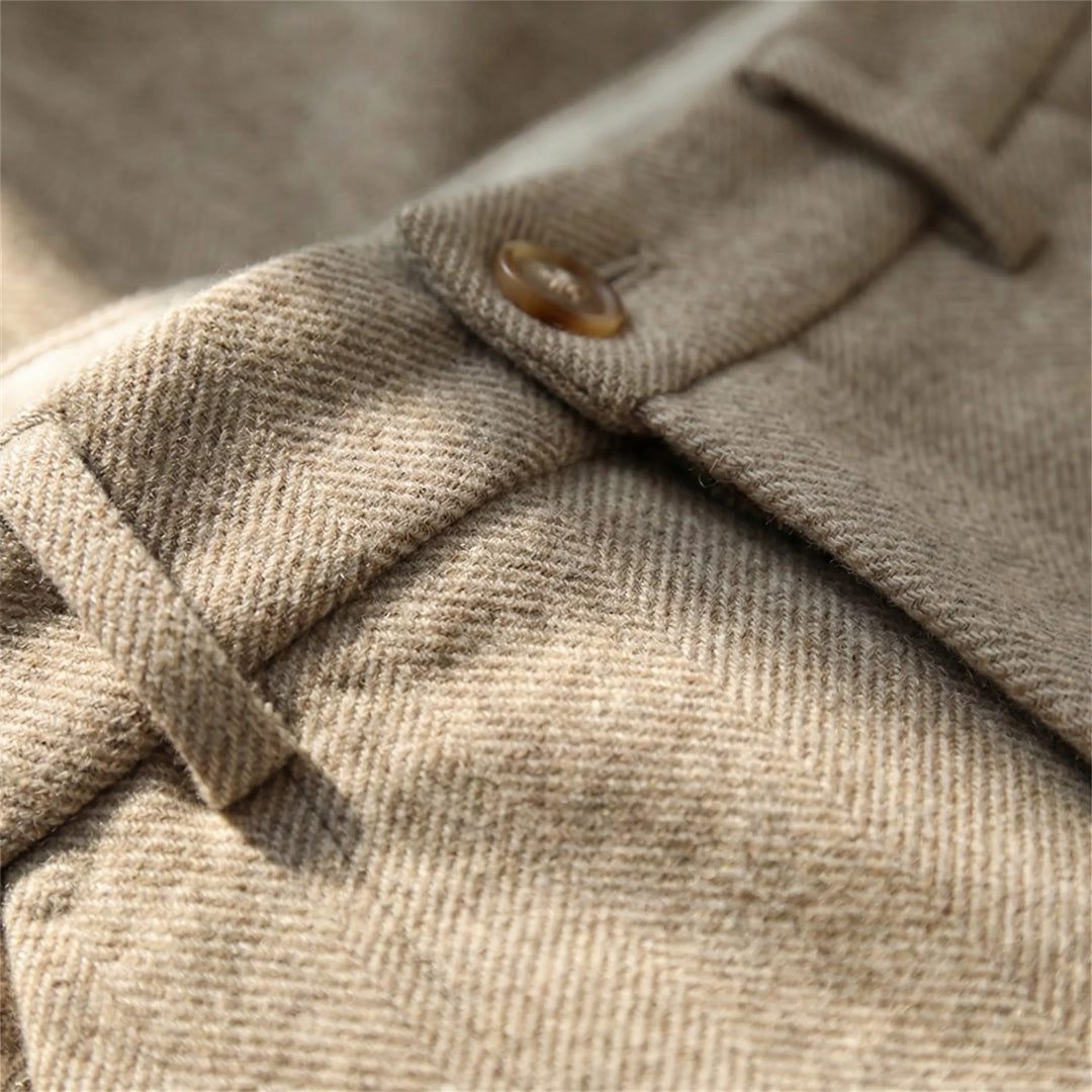 Close-up detail of the button fastening, belt loops, and herringbone weave texture on the trousers.