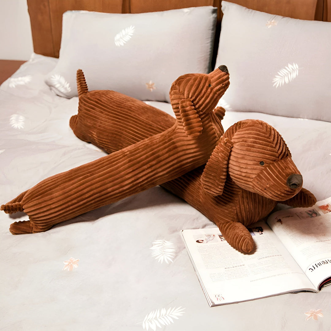 Brown dachshund plush pillows displayed on a bed with grey pillows