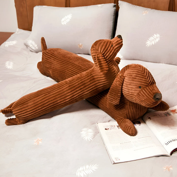 Brown dachshund plush pillows displayed on a bed with grey pillows