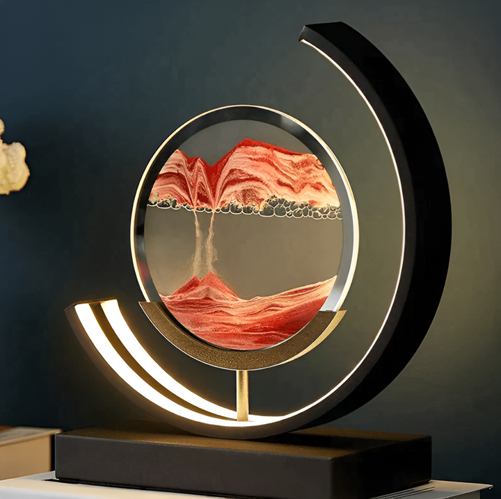 Decorative LED sand lamp displaying flowing red sand inside a circular metal frame on a dark background.