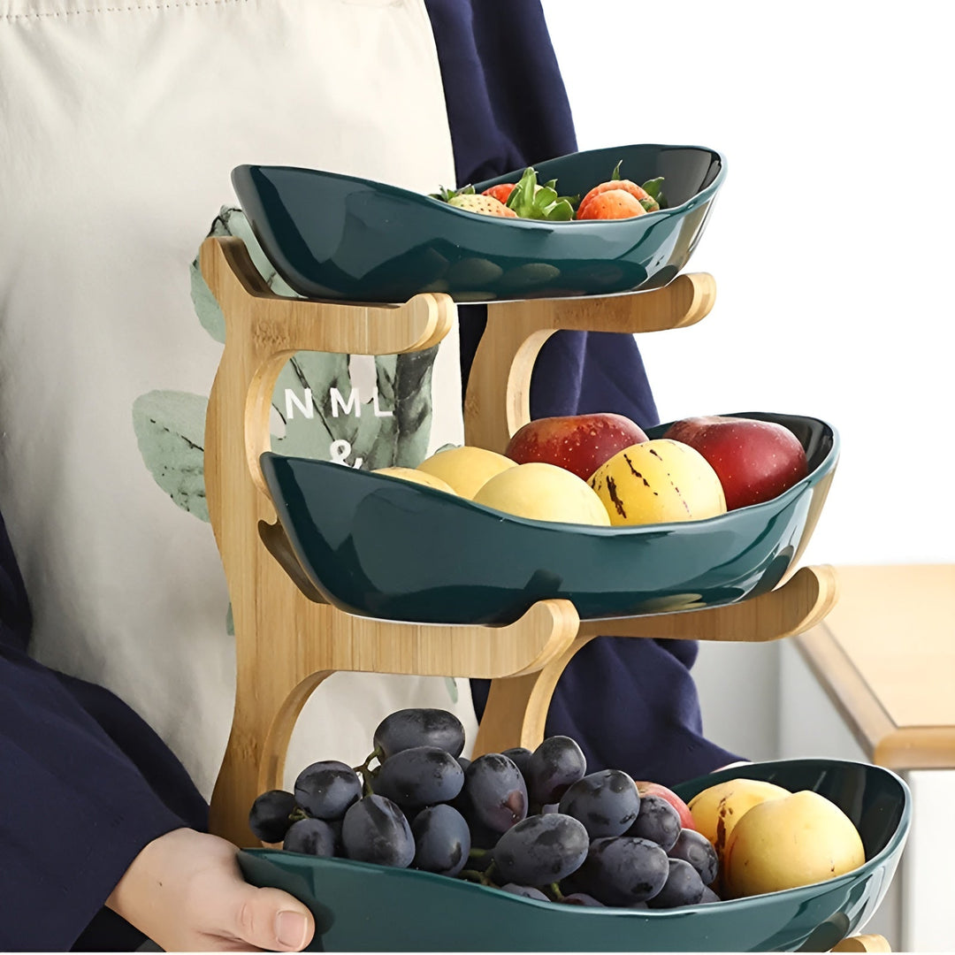 Person holding a 3-tier fruit stand filled with grapes and fruit