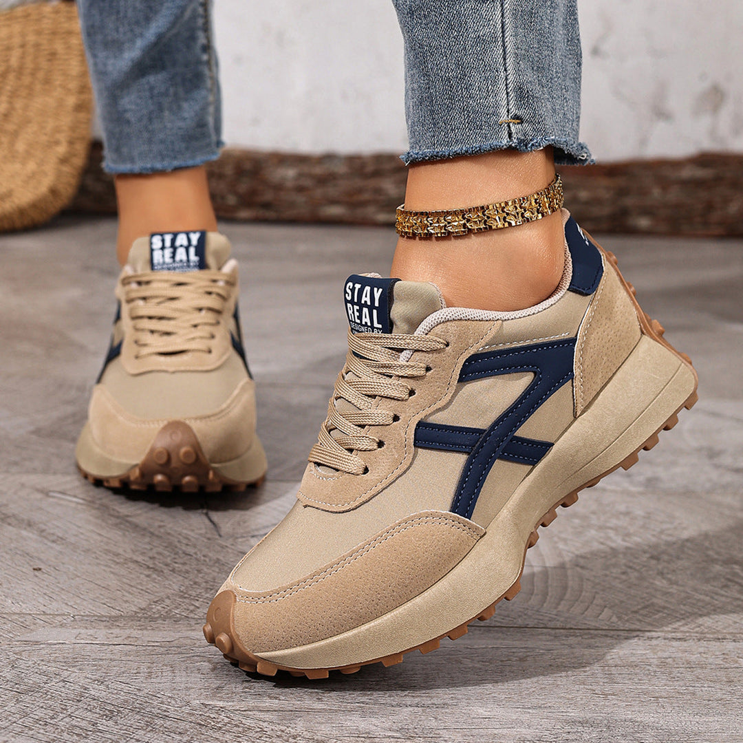 Close-up of women's beige and blue orthopedic comfort trainers worn with denim jeans.