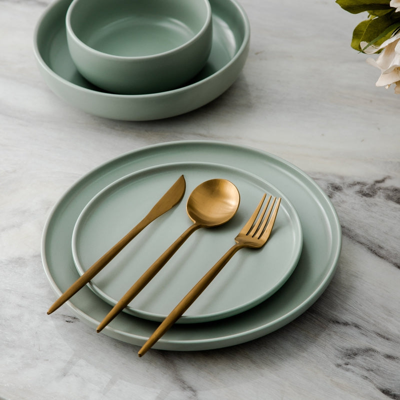 Matte gold cutlery set displayed elegantly on a dining plate with ceramic bowls