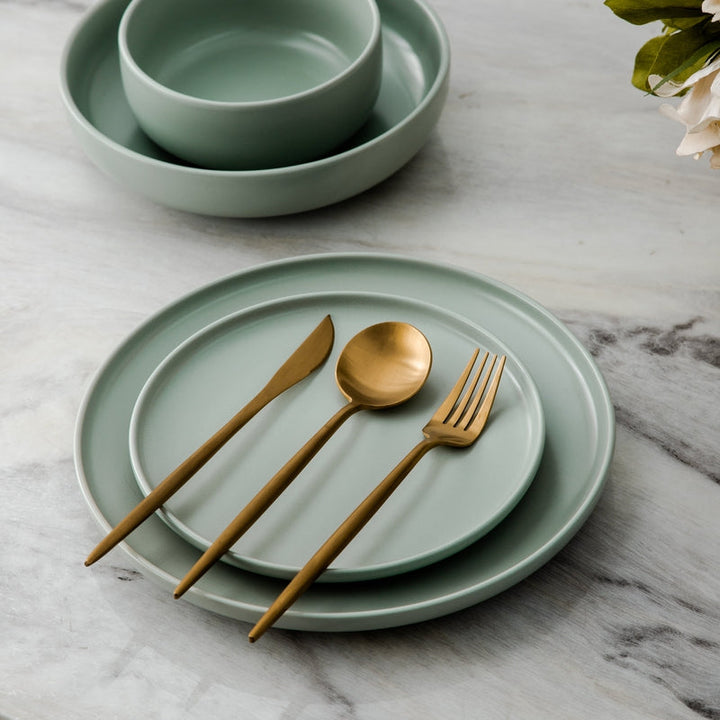Matte gold cutlery set displayed elegantly on a dining plate with ceramic bowls