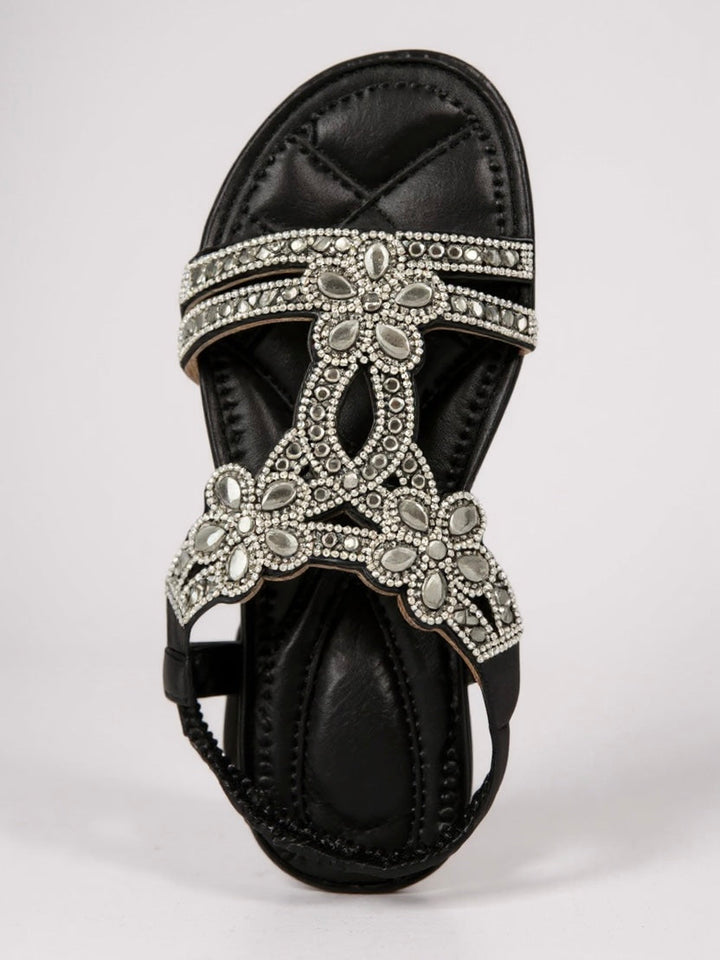 Top-down view of black sparkle sandals featuring decorative crystal flowers and straps