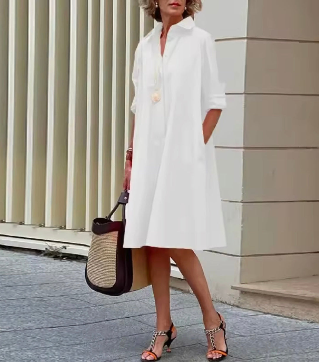 Woman wearing a crisp white shirt dress styled for casual elegance.